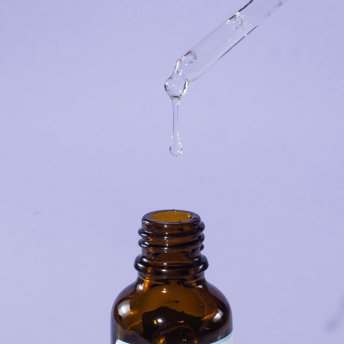 A bottle of aPAD serum on white background. The bottle is made out of glass, and has a pipette with a rubber head.
